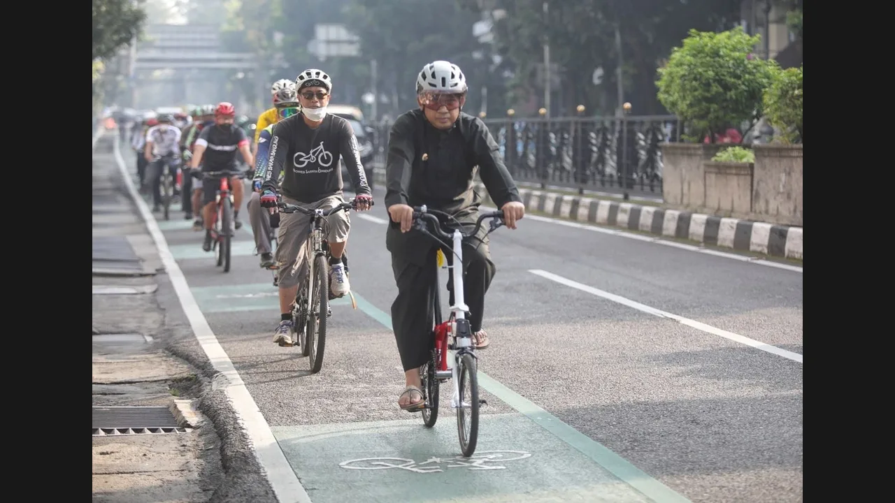 Cyclists riding in a marked bicycle lane on a Bandung street